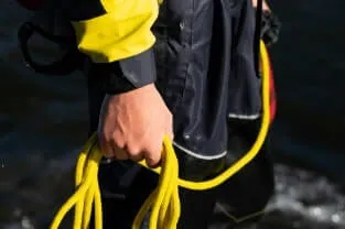 Person holding yellow kevlar rope by the water